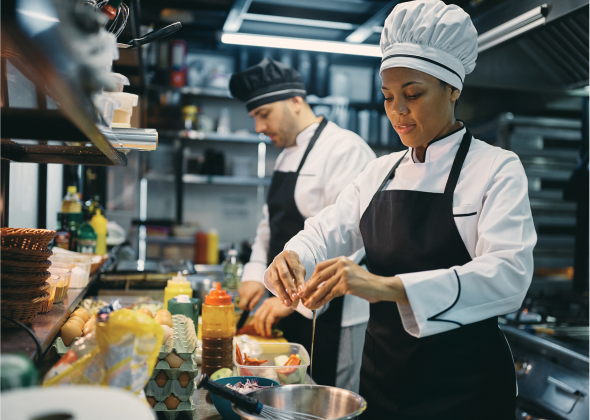 Chefs work on preparing a meal in a kitchen